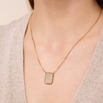 Load image into Gallery viewer, A person wearing a gold necklace with a rectangular pendant adorned with diamonds.