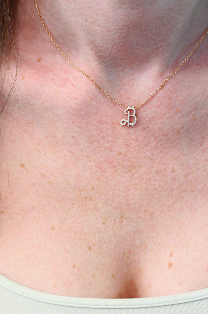 Necklace with a letter 'B' pendant on a person's neck