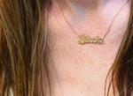Load image into Gallery viewer, A gold pendant necklace with the word 'Bitcoin' engraved in capital letters, hanging from a rolo gold link chain on model's neck.