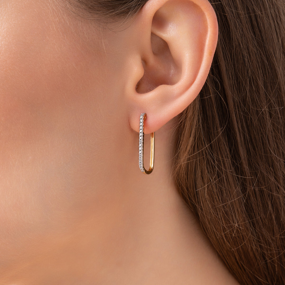 Gold hoop earrings with diamond accents on a model ear