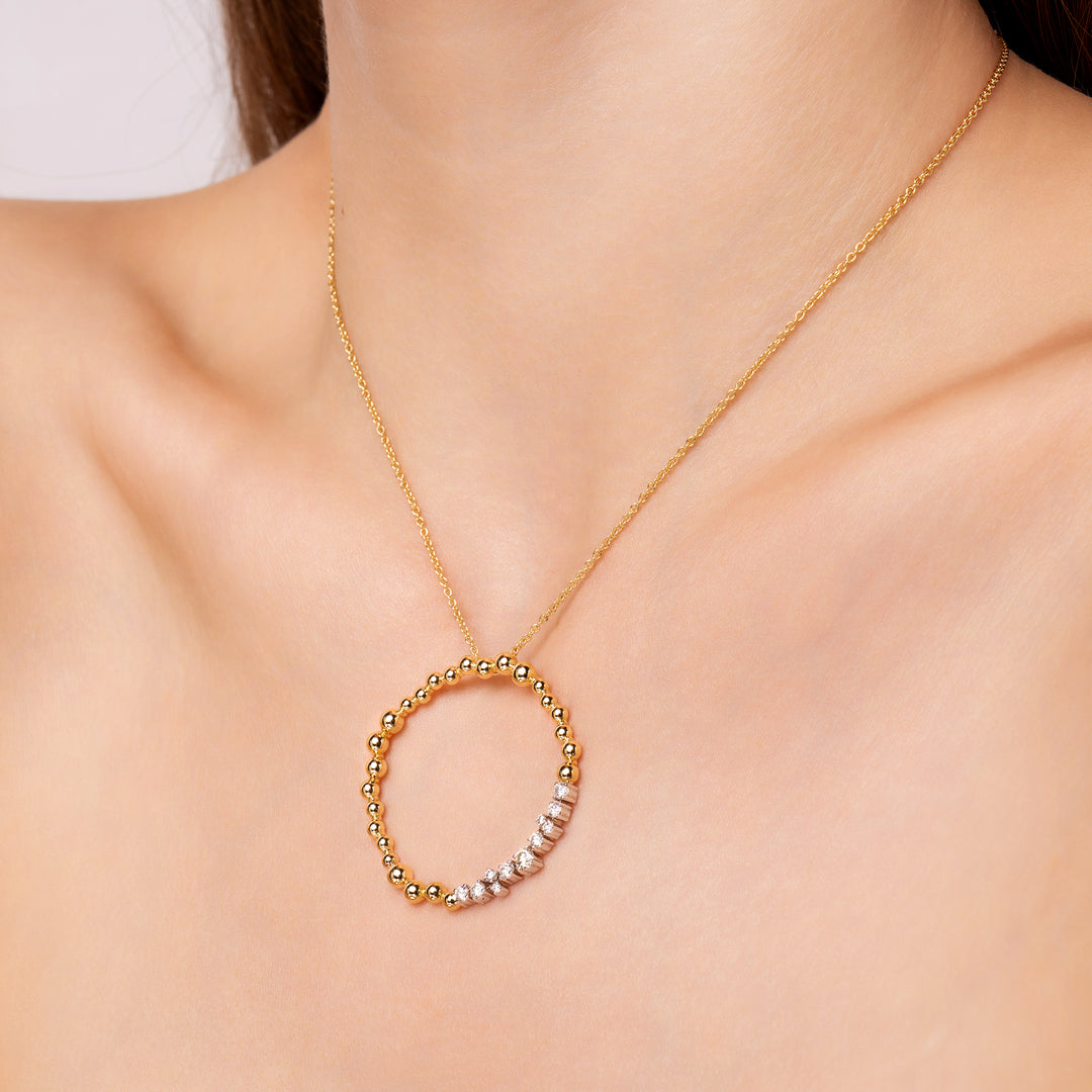 Gold necklace with a circular pendant on a model neck