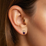 Load image into Gallery viewer, Pair of gold earrings with purple gemstones on a model ear