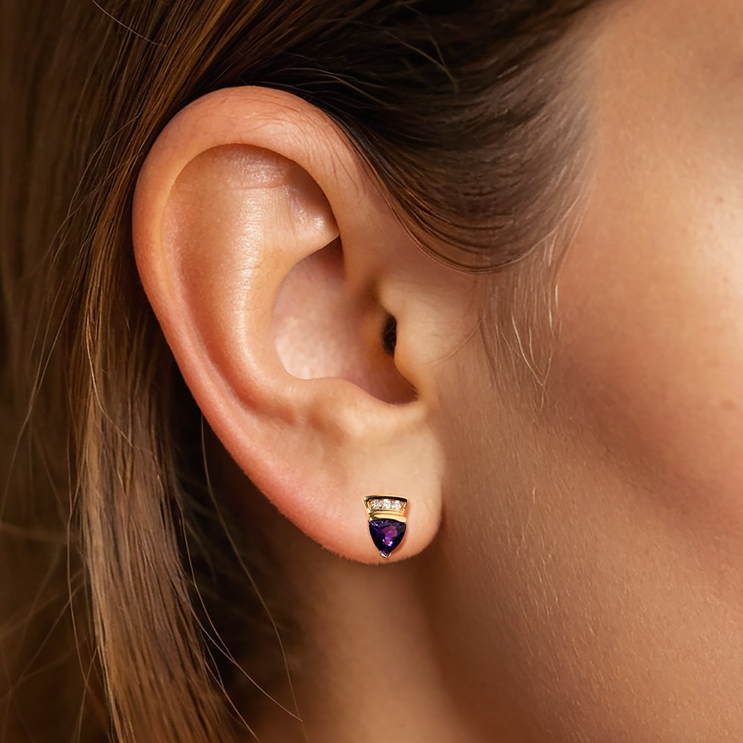 Pair of gold earrings with purple gemstones on a model ear