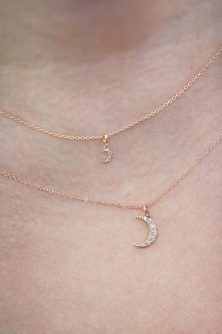 Gold necklace with a mini crescent moon and regular crescent moon pendant on model neck