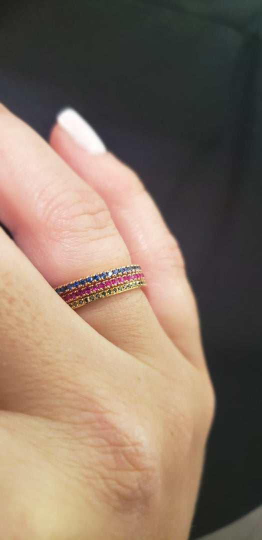 Rose gold ring with blue, pink, and green gemstones on model hand 