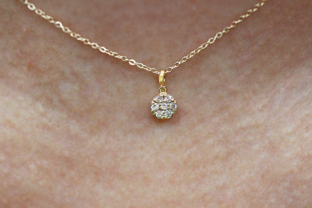 Gold necklace with a circle diamond pendant on a white background
